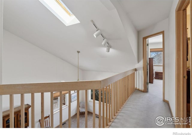 2143 Meadow Ct, Longmont, CO 80501 - hallway featuring rail lighting, light colored carpet, vaulted ceiling, and a skylight