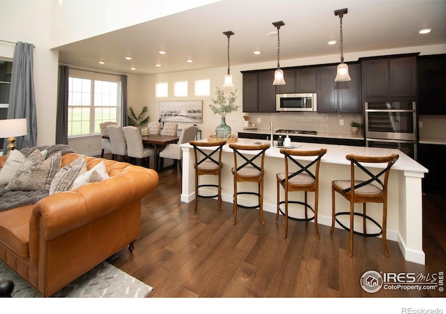 7086 Thunderview Dr, Timnath, CO 80547 - kitchen featuring stainless steel appliances, open floor plan, a kitchen breakfast bar, dark wood finished floors, and recessed lighting