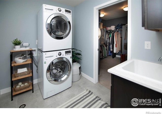 7086 Thunderview Dr, Timnath, CO 80547 - clothes washing area featuring stacked washer / dryer, cabinet space, baseboards, and light tile patterned flooring