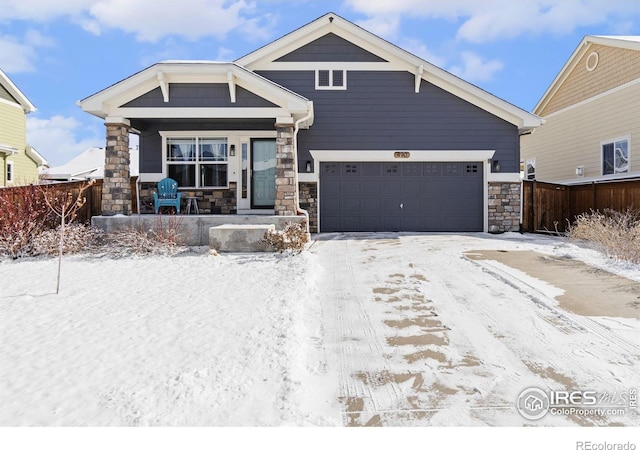 craftsman inspired home featuring an attached garage, covered porch, stone siding, and fence