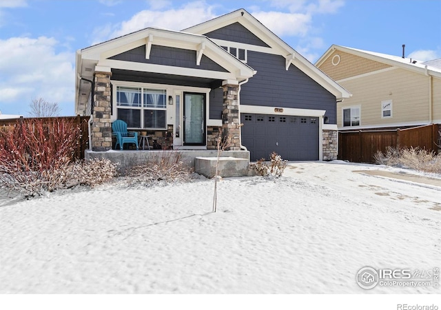 craftsman-style home featuring a garage, stone siding, and fence