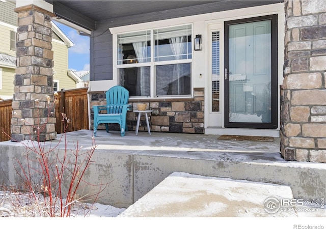 doorway to property featuring covered porch and stone siding