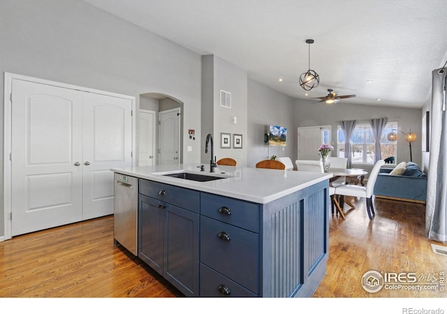 kitchen with decorative light fixtures, a center island with sink, light countertops, a sink, and dishwasher