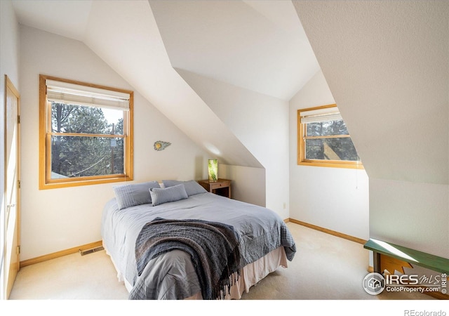 bedroom with light colored carpet, multiple windows, and lofted ceiling