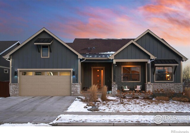 view of front of property with driveway, stone siding, a garage, and board and batten siding