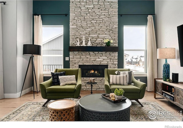 living room with a fireplace, light wood finished floors, and a wealth of natural light