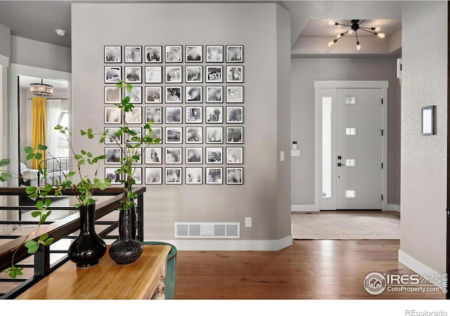 entrance foyer featuring a notable chandelier, baseboards, visible vents, and hardwood / wood-style flooring