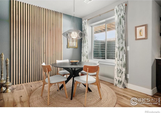 dining room with light wood-type flooring, baseboards, and an inviting chandelier