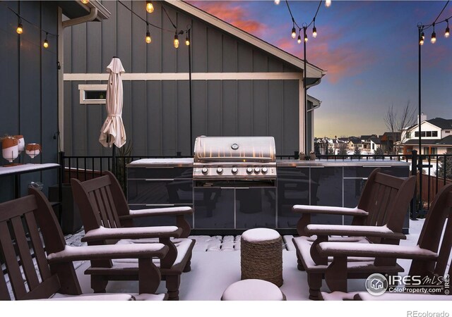patio terrace at dusk featuring area for grilling and a balcony