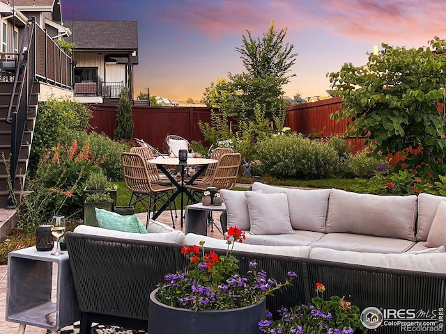 patio terrace at dusk with a fenced backyard, outdoor dining area, and an outdoor living space