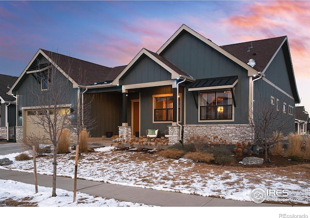 view of front of home with a porch, a garage, board and batten siding, and stone siding