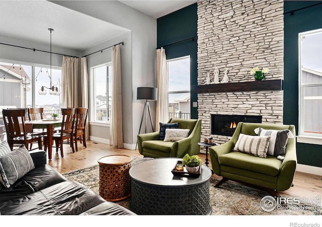 living room featuring baseboards, a stone fireplace, and wood finished floors