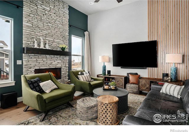 living area with ceiling fan, wood finished floors, and a fireplace