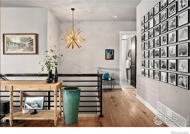 hall with a notable chandelier, baseboards, an upstairs landing, wood finished floors, and vaulted ceiling