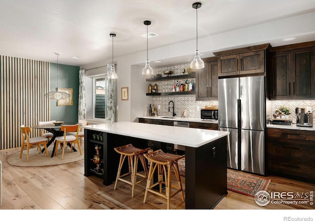kitchen featuring freestanding refrigerator, open shelves, a kitchen island, black microwave, and a sink