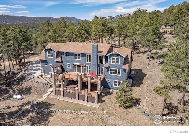 rear view of house with a deck with mountain view and a chimney