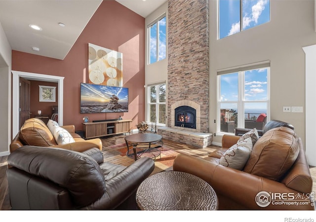 living room featuring recessed lighting, a healthy amount of sunlight, a fireplace, and wood finished floors