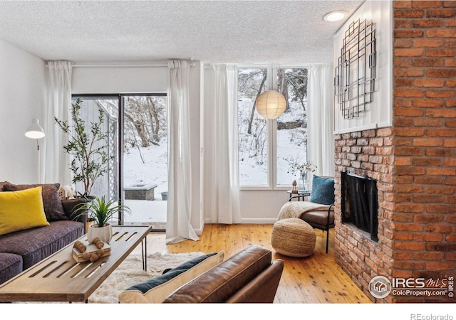 living area featuring a fireplace, light wood-style flooring, and a textured ceiling