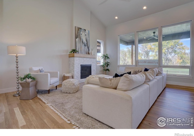 living room featuring a fireplace, plenty of natural light, wood finished floors, and a ceiling fan