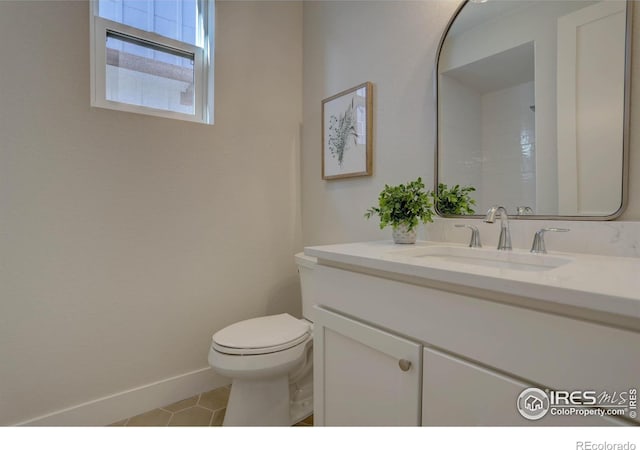 bathroom with toilet, vanity, baseboards, and tile patterned floors