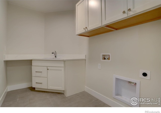 washroom with cabinet space, baseboards, hookup for a washing machine, electric dryer hookup, and a sink