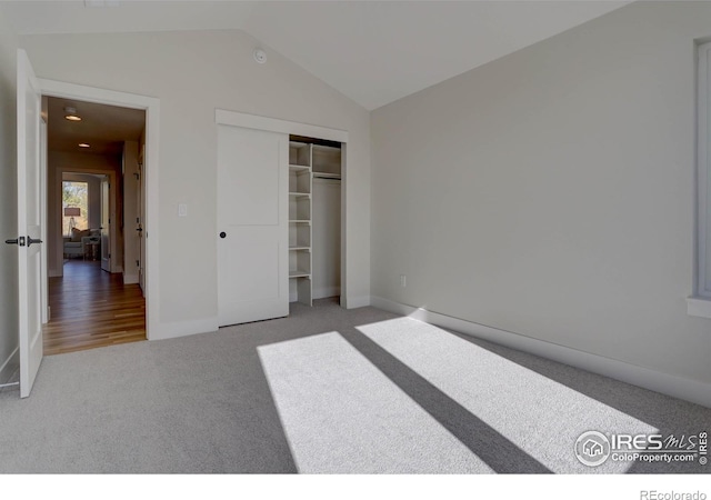 bedroom featuring lofted ceiling, a closet, carpet, and baseboards