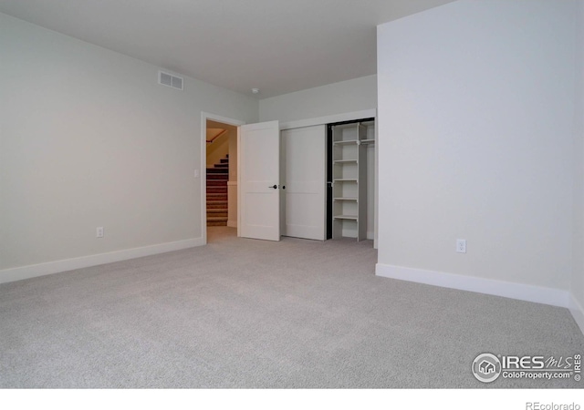 unfurnished bedroom with light colored carpet, a closet, visible vents, and baseboards