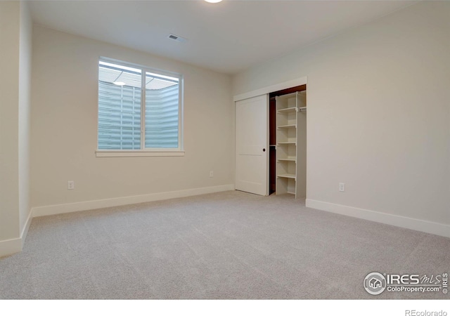 unfurnished bedroom featuring baseboards, a closet, visible vents, and light colored carpet