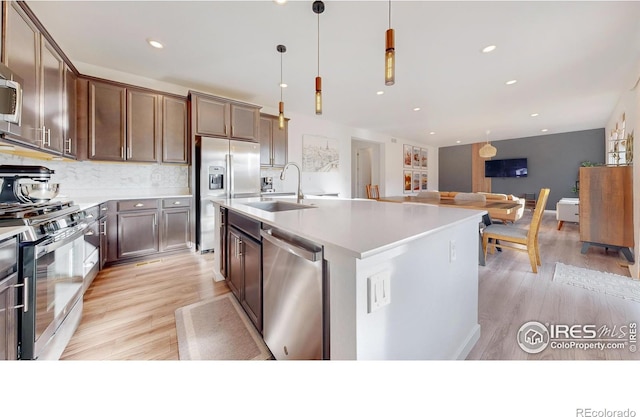 kitchen featuring a sink, tasteful backsplash, appliances with stainless steel finishes, and light wood-style flooring