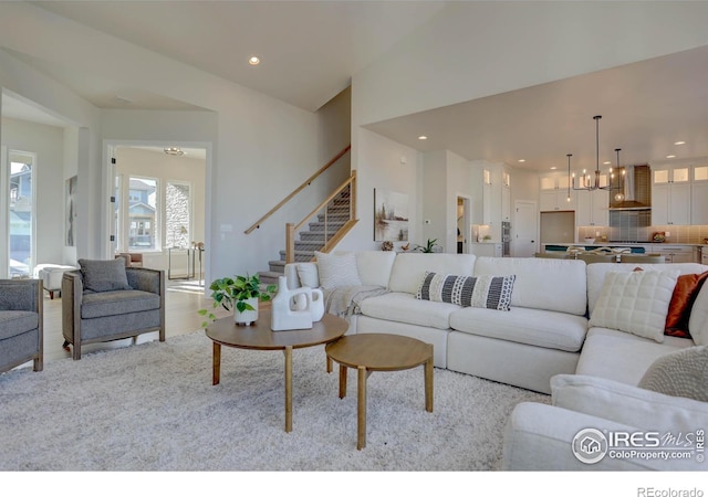 living area with an inviting chandelier, stairway, light wood-style floors, and recessed lighting