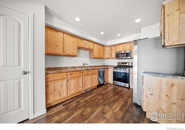 kitchen with a sink, light brown cabinetry, appliances with stainless steel finishes, and dark wood finished floors