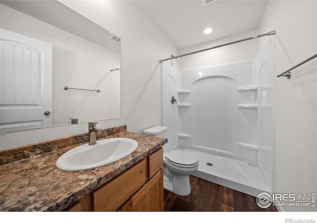 bathroom with a shower, visible vents, toilet, vanity, and wood finished floors