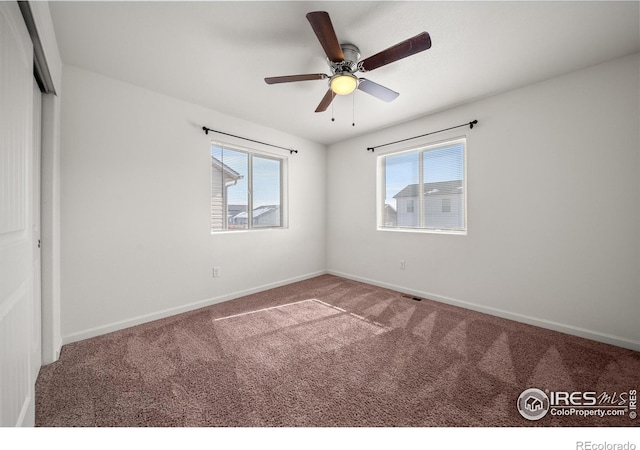 carpeted spare room featuring a ceiling fan and baseboards