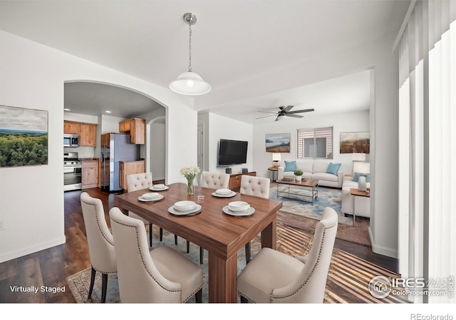 dining area with baseboards, arched walkways, dark wood finished floors, and a ceiling fan