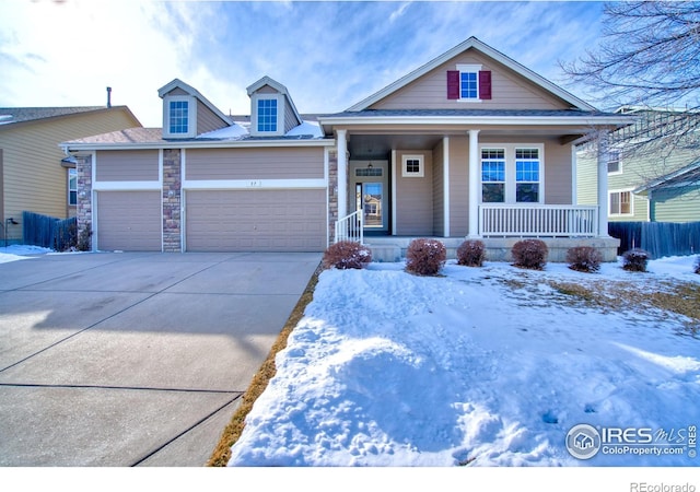 view of front of home with a porch, stone siding, driveway, and an attached garage