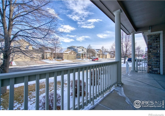 snow covered back of property with covered porch and a residential view