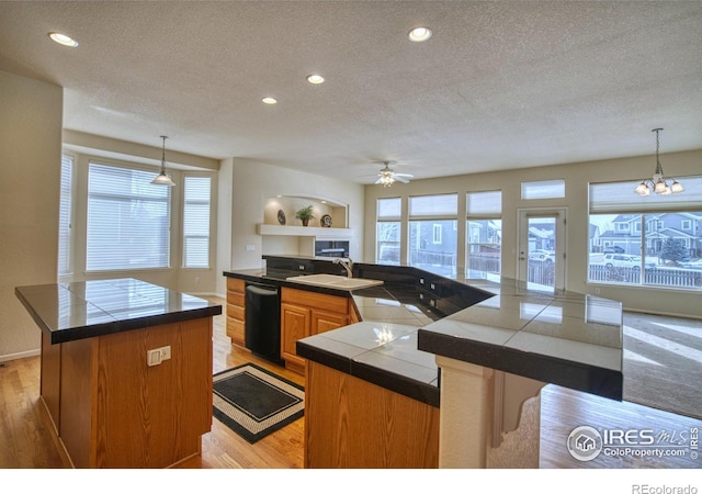 kitchen featuring brown cabinetry, tile counters, pendant lighting, and open floor plan