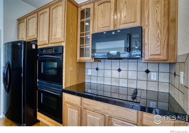 kitchen with tile countertops, black appliances, glass insert cabinets, and decorative backsplash