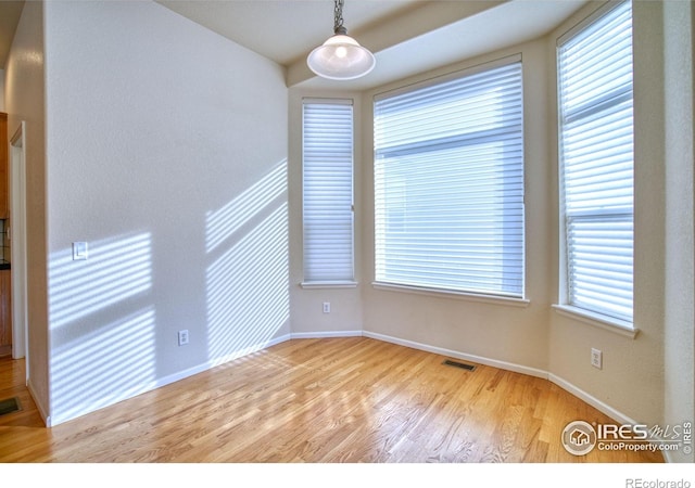 unfurnished room featuring baseboards, visible vents, and light wood finished floors