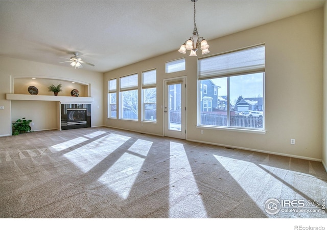 unfurnished living room with light carpet, ceiling fan with notable chandelier, baseboards, and a glass covered fireplace