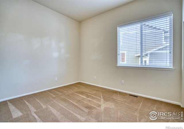 carpeted empty room featuring visible vents and baseboards