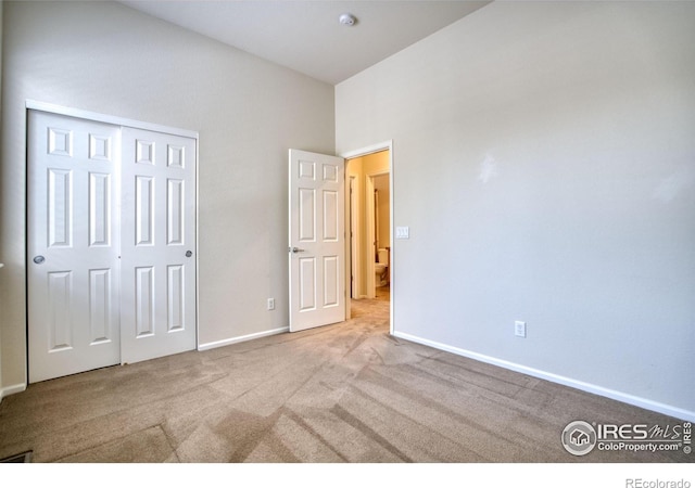 unfurnished bedroom featuring a closet, light carpet, and baseboards