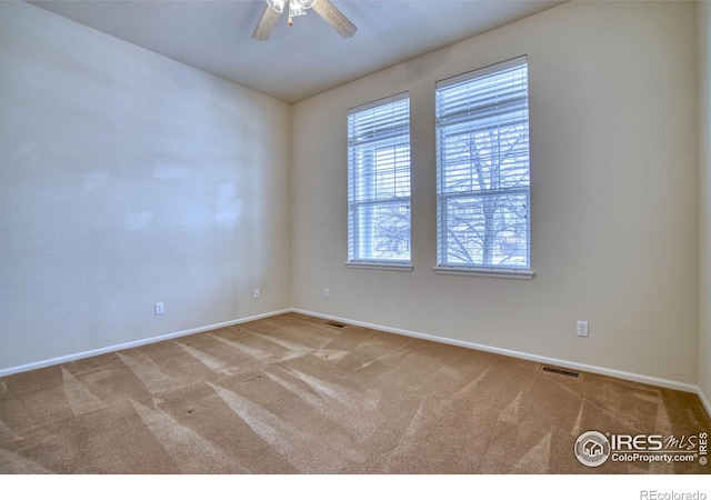 empty room featuring visible vents, carpet floors, a ceiling fan, and baseboards