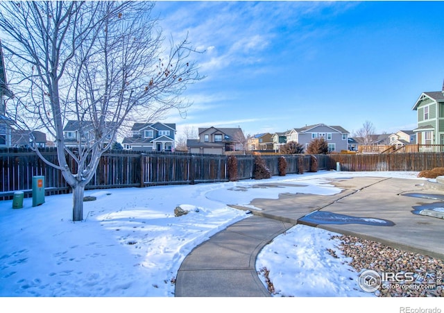 snowy yard with a residential view and a fenced backyard