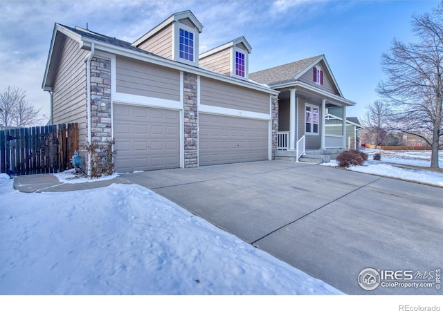 view of front of home with a garage, stone siding, fence, and concrete driveway