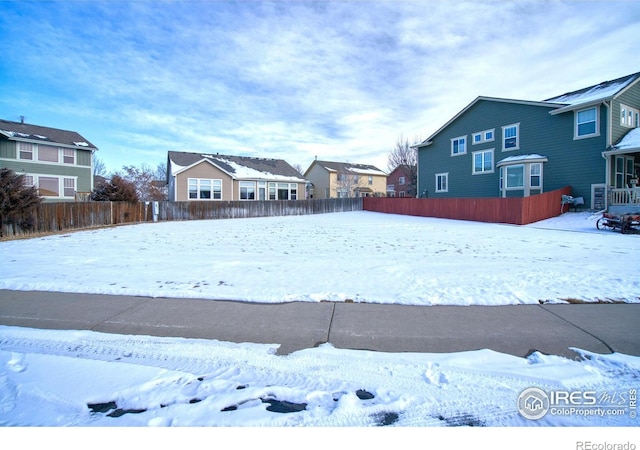 yard covered in snow featuring fence and a residential view