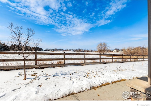 yard layered in snow with fence and a rural view