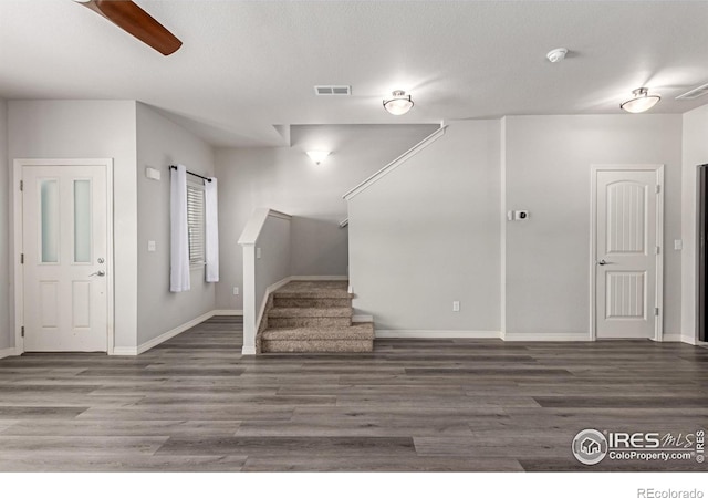 interior space with dark wood-style floors, baseboards, stairs, and visible vents