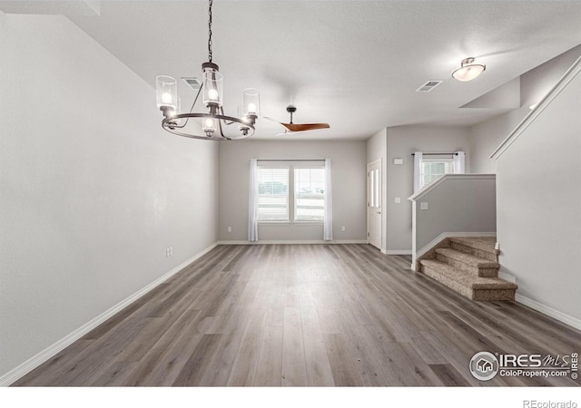 interior space featuring a chandelier, wood finished floors, visible vents, baseboards, and stairway