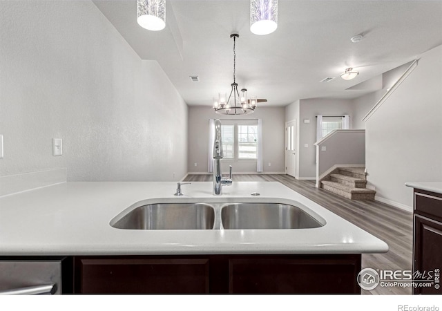 kitchen with decorative light fixtures, light countertops, open floor plan, a sink, and wood finished floors